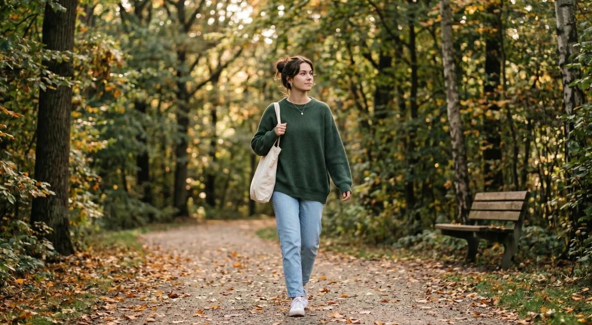 Woman walking alone on a forest path surrounded by autumn trees, representing emotional withdrawal and independence linked to avoidant attachment style_