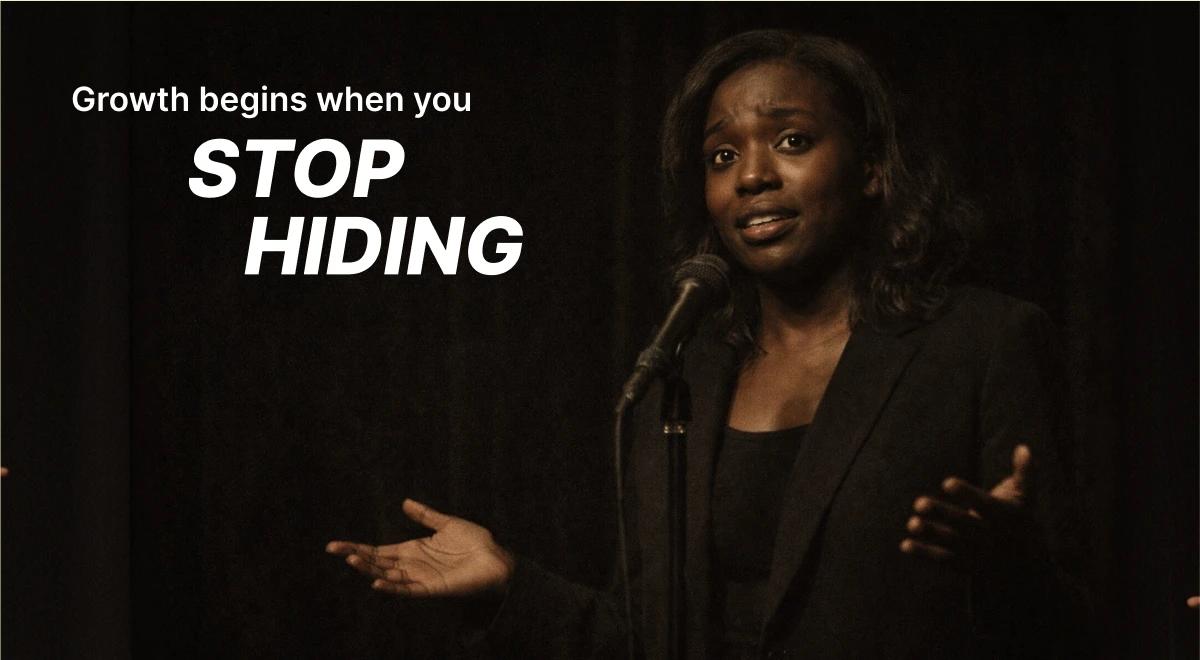 Black woman in a dark blazer speaking confidently at a microphone on stage, representing the courage to stop hiding and face fear to achieve growth