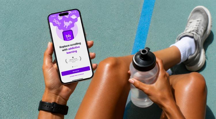 Woman sitting on sports court holding smartphone with self-improvement app and water bottle, wearing sneakers and smartwatch