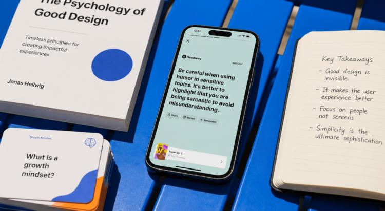 Smartphone showing Headway app insight on a blue table beside design books and notebook, illustrating microlearning vs s