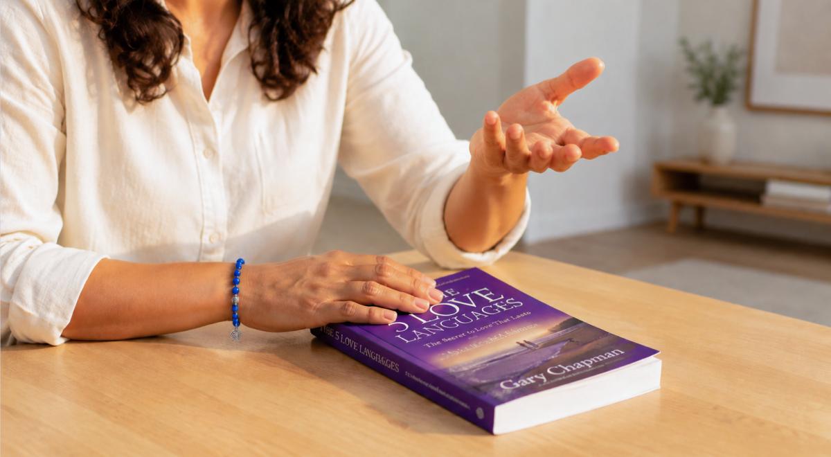 Manos de mujer junto al libro Los 5 Lenguajes del Amor de Gary Chapman sobre una mesa, recurso para mejorar la comunicación en pareja