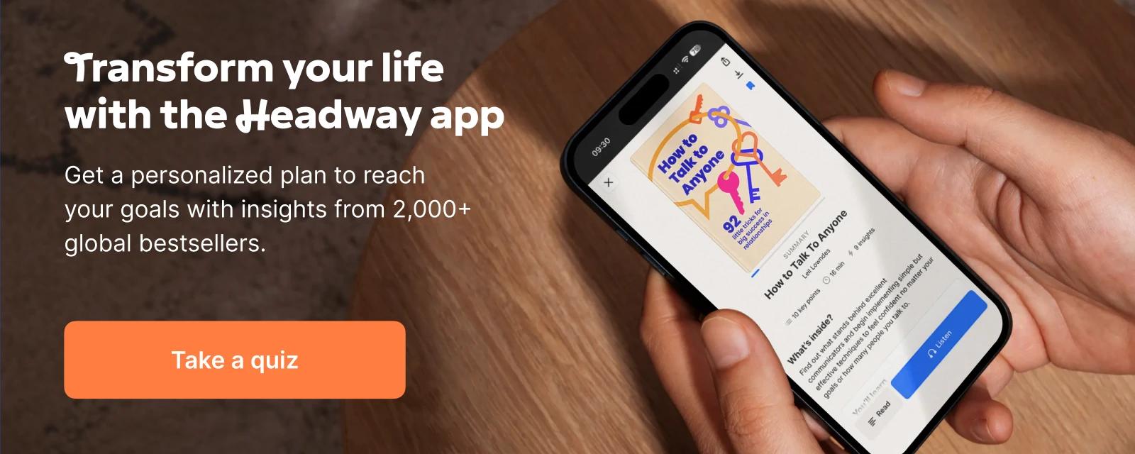 Close-up of a hand holding a smartphone displaying the How to Talk to Anyone book summary in the Headway learning app, against a wooden surface background
