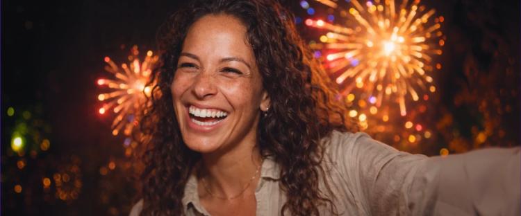 Joyful woman celebrating with bright orange and purple fireworks on dark night sky expressing happiness and personal growth