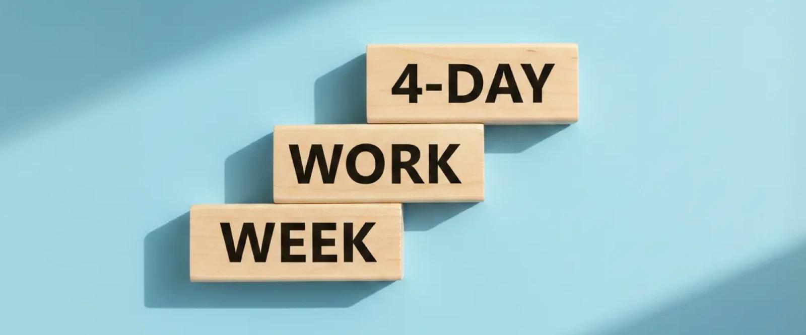 Three wooden blocks arranged in stair-step formation on a light blue background, each labeled to spell out _4-day work week,_ symbolizing the shift to a shorter, more productive work schedule
